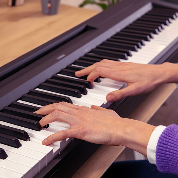 Frau spielt auf Yamaha P 145 E-Piano mit gewichteten Tasten
